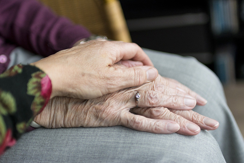 Person holding elderly person's hand
